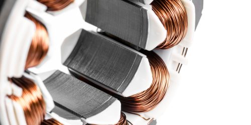 Detail of copper winding, stack and shaft of a  electric permanent magnet motor for home appliances. Selective focus and white background.